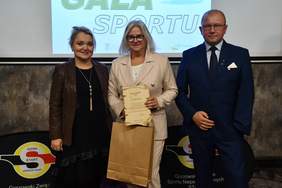 Pokaż zdjęcie: Trzy osoby, w tym dwie kobiety, podczas okolicznościowego zdjęcia na Gali, stoją obok siebie na tle logo Start Gorzów