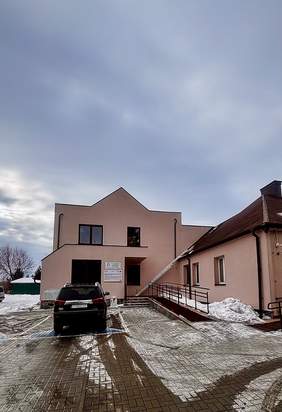 Pokaż zdjęcie: Budynek ośrodka rehabilitacyjno-edukacyjno-wychowawczego z podjazdem dla osób z niepełnosprawnościami; przed budynkiem znajduje się parking i samochód, widoczna zimowa sceneria.