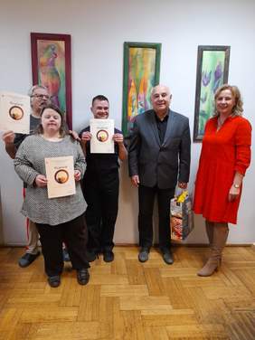 Pokaż zdjęcie: Zdjęcie na korytarzu, pięć osób pozuje do zdjęcia, trzy z nich prezentują dyplomy w konkursie plastycznym