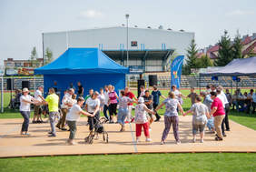 Grupa osób tańczących w kole, w plenerze, jasny słoneczny dzień