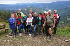 Pokaż zdjęcie: uczestnicy zlotu turystycznego 2020 na szczycie góry, a w oddali piękna panorama pasma gór