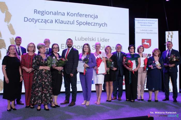 Pokaż zdjęcie: Na scenie stoi grupa laureatów, pozują do pamiątkowego zdjęcia.
