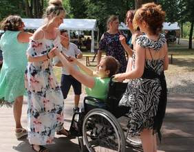 Pokaż zdjęcie: Uczestniczka festiwalu na wózku tańczy z opiekunami 