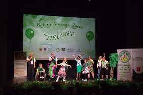 Pokaż zdjęcie: Na scenie artyści ubrani na zielono. W tle napis "Kolory naszego życia - ZIELONY" 