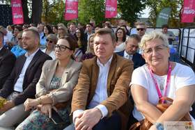 Uczestnicy Chmielaków Krasnostawskich siedzą na widowni podczas wydarzenia plenerowego. W tle widoczne są flagi RMF MAXX oraz zgromadzona publiczność.