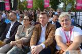 Uczestnicy Chmielaków Krasnostawskich siedzą na widowni podczas wydarzenia plenerowego. W tle widoczne są flagi RMF MAXX oraz zgromadzona publiczność.
