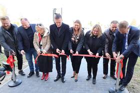 Goście uroczystości, ubrani na galowo, przecinają wstęgę symbolizując otwarcie placówki
