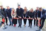 Goście uroczystości, ubrani na galowo, przecinają wstęgę symbolizując otwarcie placówki