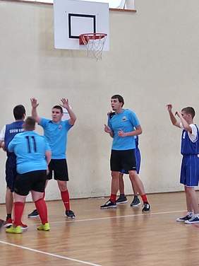 Pokaż zdjęcie: Najlepszy z zawodników z Łupek (granatowe strój) powstrzymywany jest przez trzech zawodników z Kartuz przed rzutem do kosza (niebieskie stroje)