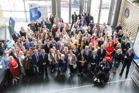 Pokaż zdjęcie: Zdjęcie grupy osób biorących udział w lubelskim forum, stojących w zwartej grupie, zdjęcie robione z balkonu  