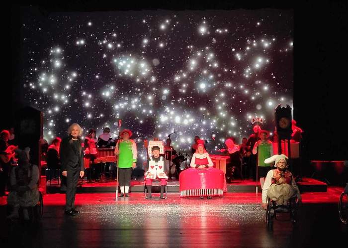 Pokaż zdjęcie: Aktorzy na scenie w trakcie spektaklu. W tle ekran z wizualizacjami i światło w czerwonej barwie