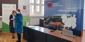 Na sali Starostwa Powiatowego w Wąbrzeźnie Dyrektor Kuajwsko-Pomorskiego Oddziału PFRON składa gratulacje i wręcza upominek laureatce konkursu plastycznego