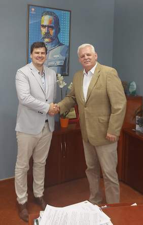 Pokaż zdjęcie: Dyrektor Szkaradziński (w jasnym garniturze) ściska dłoń Dyrektorowi Kierozalskiemu (brązowy garnitur). W tle obraz z obliczem Piłsudskiego