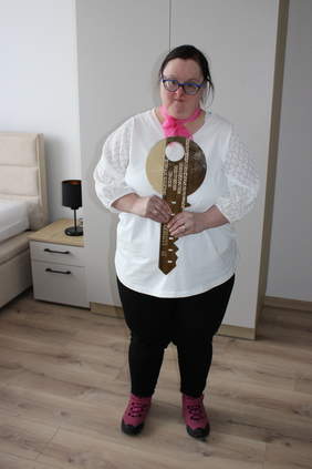 Pokaż zdjęcie: Kobieta stojąca na środku trzymająca w ręku duży klucz