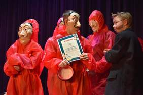 Pokaż zdjęcie: Młodzież w czerwonych kombinezonach i w maskach scenicznych