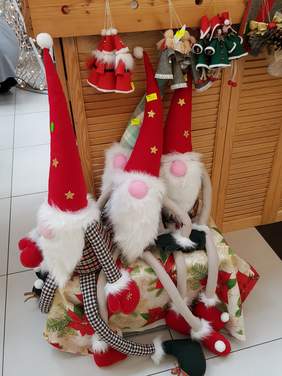 pod stoiskiem siedzą 3 skrzaty z długimi rękami i nogami, w czerwonych czapkach