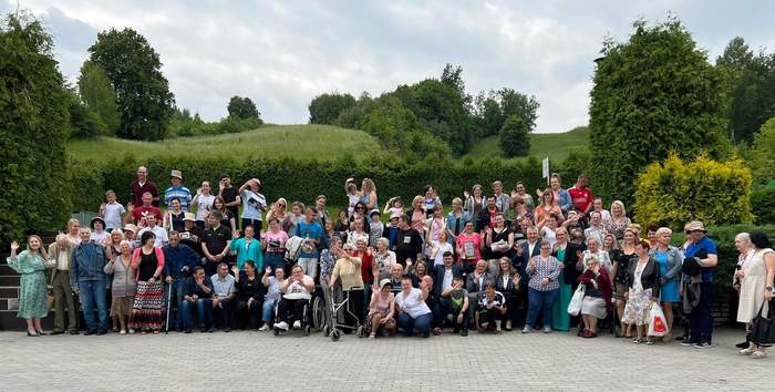 Pokaż zdjęcie: Na zdjęciu ponad sto uśmiechniętych osób stoi na tle lasu
