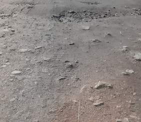 Pokaż zdjęcie: U góry szara droga z wystającymi, lekko połyskującymi kamieniami. Na środku biały, poziomy pasek oddzielający tło w kolorze odcienia ciemnego brązu z domieszką lekko połyskujących białych malutkich kropek.