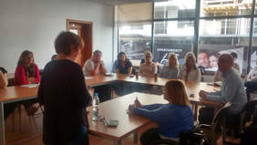 Pokaż zdjęcie: Osoby siedzące za stołami słuchające wykładu. 