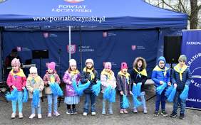 Pokaż zdjęcie: Występy artystyczne grup przedszkolnych, dzieci trzymają w rękach niebieskie pompony, śpiewają