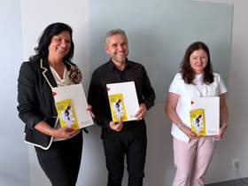 dwie kobiety i mężczyzna pozują do zdjęcia, trzymają teczki z porozumieniem.