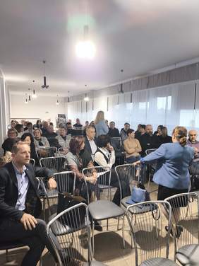 Pokaż zdjęcie: Zdjęcie uczestników konferencji siedzących na krzesłach.