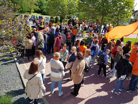 widok z góry na tłum zebranych ludzi, pomarańczowe elementy ubrań, balony, słoneczny dzień