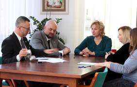 Pokaż zdjęcie: Przy stole siedzą dwaj mężczyźni i trzy kobiety podpisują dokumenty.