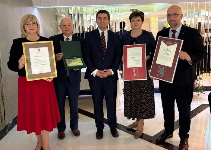 Pokaż zdjęcie: Pięć osób, dwie kobiety i trzech mężczyzn trzymają w rękach dyplomy lub grawertony. 