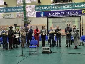 Na środku sali stoją zaproszeni goście - osoby wyróżnione przez gospodarzy za wkład i pomoc w rozwój podmiotu.