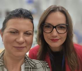 Pokaż zdjęcie: Dwie uśmiechnięte kobiety pozują do zdjęcia.