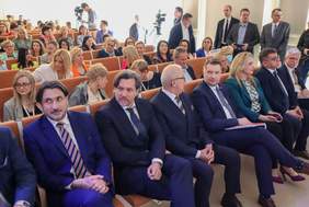 Pokaż zdjęcie: W sali konferencyjnej, w pierwszym rzędzie, w zdecydowanej większości siedzą mężczyźni w garniturach , w tym między innymi Minister Edukacji i Nauki Przemysław Czarnek. W pozostałych rzędach dominują natomiast kobiety. Na sali widoczni są także dziennikarze oraz dwie kamery, za pośrednictwem których relacjonowana jest konferencja.