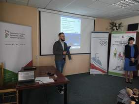 Pokaż zdjęcie: Młody mężczyzna z brodą prowadzi wykład.