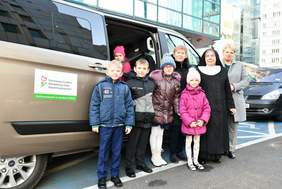 Pokaż zdjęcie: Uczniowie z opiekunką, pracownicy oddziału na tle dofinansowanego samochodu.