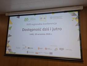 Pokaż zdjęcie: Na tablicy multimedialnej wyświetlone są informacje dotyczące konferencji. Są także loga organizatorów i partnerów. 