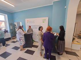 Zaproszeni goscie stoją wokół stolików barowych i rozmawiają