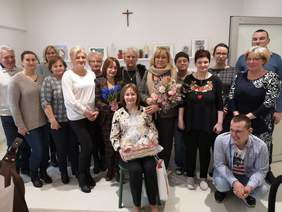 Pokaż zdjęcie: Podopieczni oraz goście w jednej z sal ośrodka wspólnie pozują do zdjęcia. 