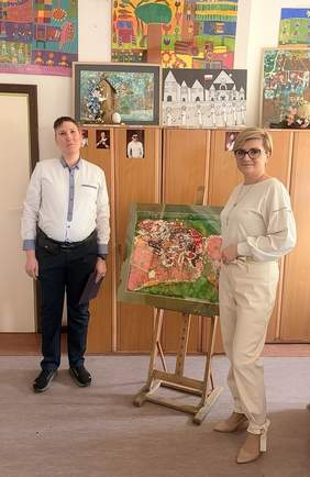 Pokaż zdjęcie: Krzysztof Drapczuk, laureat konkursu plastycznego, oraz Edyta Kondzior, Dyrektor Podlaskiego Oddziału PFRON, stoją przy nagrodzonej pracy prezentowanej na sztaludze.