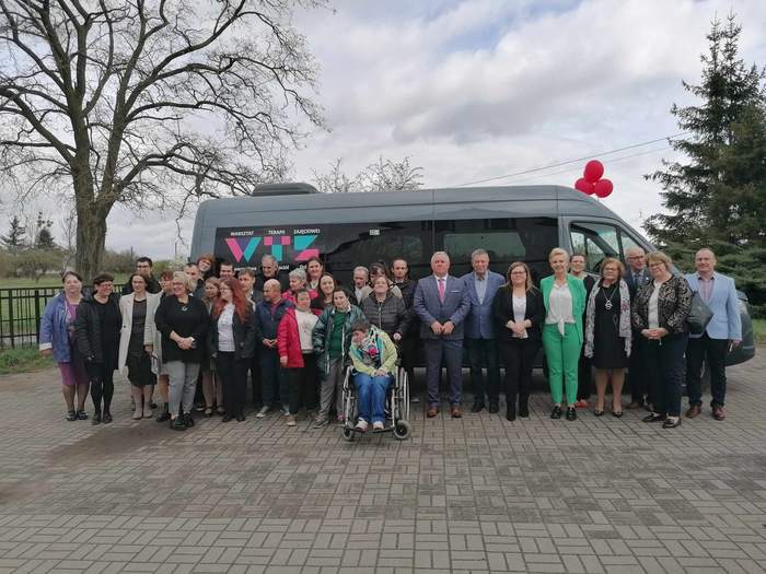 Zdjęcie grupowe uczestników uroczystości, w tle widać nowy autobus