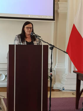 Kobieta na mównicy, za mikrofonem nad nią napis MOST