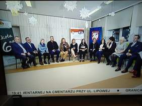 Pokaż zdjęcie: W pokoju na krzesłach siedzą osoby i rozmawiają. Rozmowę prowadzi pani redaktor.