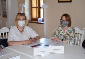 Pokaż zdjęcie: Od lewej: Dyrektor - Marta Mordarska oraz ekspert - Bogusława Słońska. Panie siedzą przy stole. Na twarzach mają maseczki