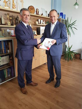 dwóch mężczyzn, stoją, podają sobie dłonie, uśmiechają się