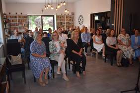 Pokaż zdjęcie: Zdjęcie osób siedzących na krzesełkach, są to zarówno goście jak i mieszkańcy Domu Pomocy Społecznej w Kostomłotach.