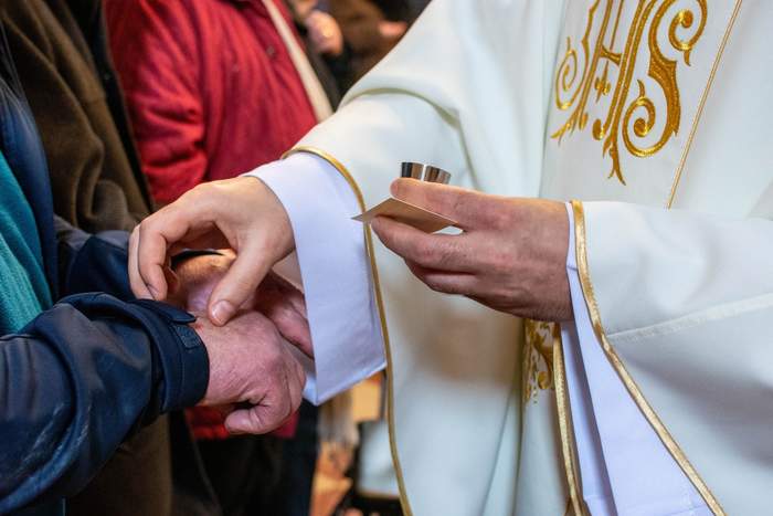 Pokaż zdjęcie: Ksiądz udziela sakramentu namaszczenia chorych, smarując ręce olejami