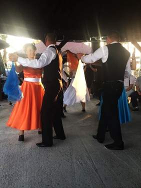 Odświętnie i kolorowo ubrane pary tańczą na scenie