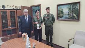 Pokaż zdjęcie: Do zdjęcia stanęły trzy osoby: dyrektor Łódzkiego Oddziału PFRON i dwóch harcerzy. Jeden z harcerzy trzymaw dłoniach Betlejemskie Światło Pokoju. Na stole stoją świąteczne stroiki. 