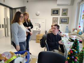 Pokaż zdjęcie: Pani Dyrektor zwiedza jedną z pracowni, osoby siedzą przy biurkach, pani dyrektor stoi przy nich.