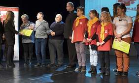 Na scenie stoją osoby obdarowane, ks. Daniel Adamowicz i uczestnicy akcji Caritas