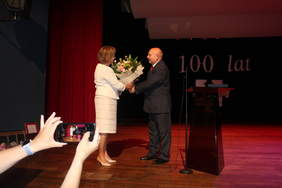 Pokaż zdjęcie: Mężczyzna na scenie wręcza bukiet kwiatów kobiecie